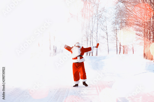 Fototapeta Naklejka Na Ścianę i Meble -  Santa in the winter field. Santa magical fog is walking along the field. Santa on Christmas Eve is carrying presents to children in a red bag.