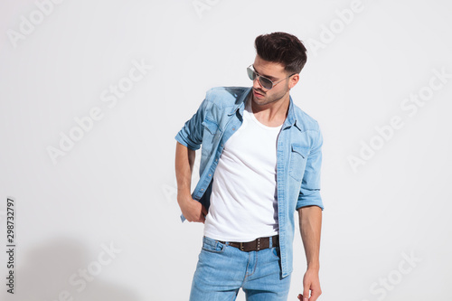 Young fashion man holding adjusting his jacket