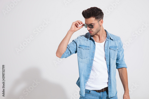 Confident fashion man taking off his sunglasses
