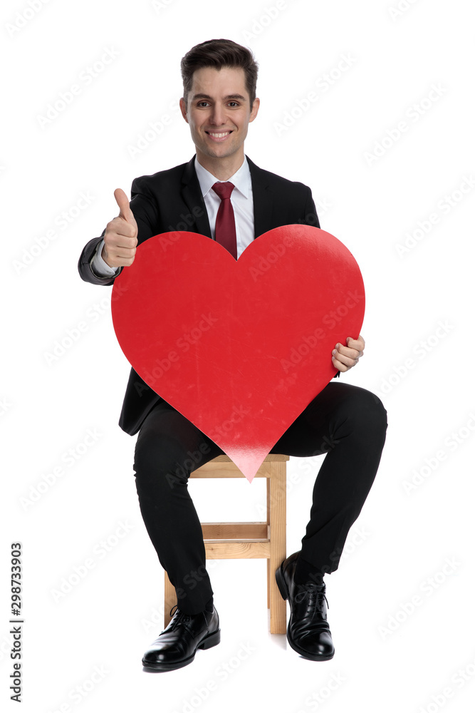Cheerful businessman holding a heart shape and giving thumbs up Cheerful businessman holding a heart shape and giving thumbs up