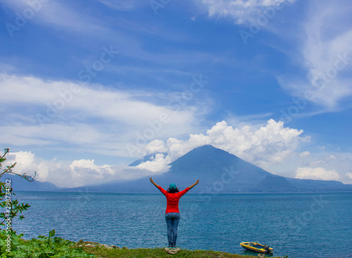 Libertad. Mujer con los brazos extendidos frente al Lago de Atitlán y el Volcán Tolimán
