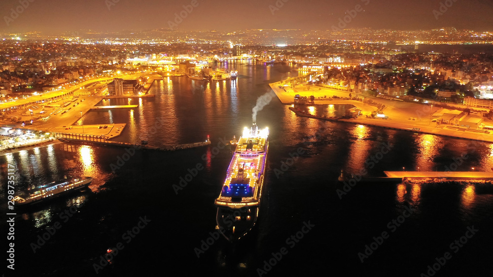 Aerial drone night shot of beautiful illuminated port of Piraeus and huge cruise liner departing to Aegean popular destinations, Attica, Greece - obrazy, fototapety, plakaty 