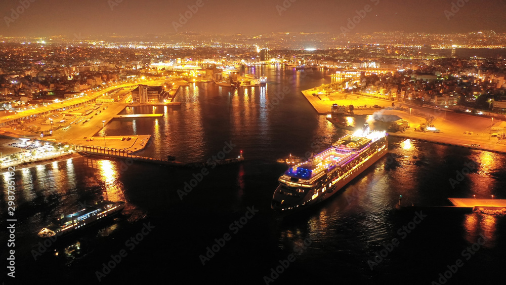 Aerial drone night shot of beautiful illuminated port of Piraeus and huge cruise liner departing to Aegean popular destinations, Attica, Greece Aerial drone night shot of beautiful illuminated port of Piraeus and huge cruise liner departing to Aegean popular destinations, Attica, Greece