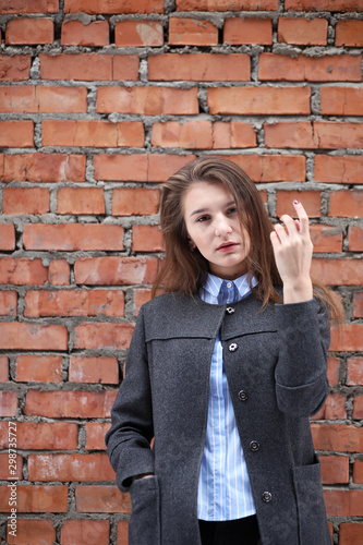 Young beautiful girl near red brick wall posing