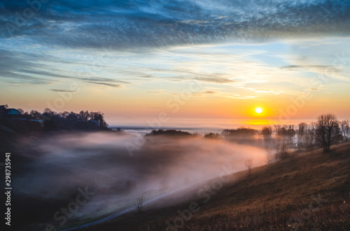 Foggy morning in the village. Bright fine sunrise. Colourful sunrise outdoors.