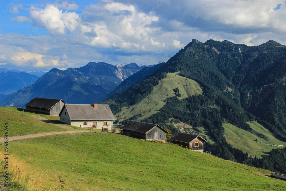 Fabulously beautiful European cozy landscape in the cozy Alps mountains in Liechtenstein on the border with Austria. A lonely farmhouse among mountains, alpine meadows and trees on a bright sunny day.
