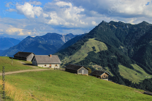Fabulously beautiful European cozy landscape in the cozy Alps mountains in Liechtenstein on the border with Austria. A lonely farmhouse among mountains, alpine meadows and trees on a bright sunny day.