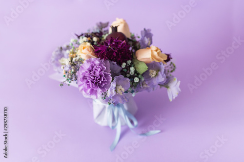 A spring gentle bouquet of mixed flowers on a purple background. First meeting bouquet or 8 of march concept.