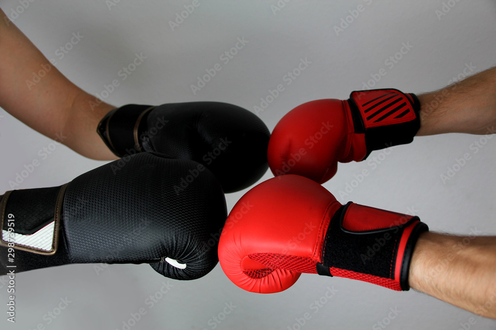close-up hands of two boxers in red and black boxing gloves closed for sports greeting on a light background with space for copy text