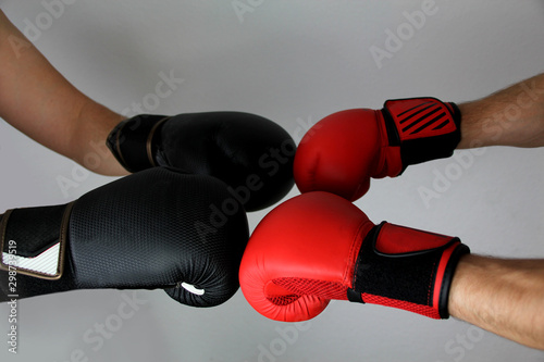 close-up hands of two boxers in red and black boxing gloves closed for sports greeting on a light background with space for copy text