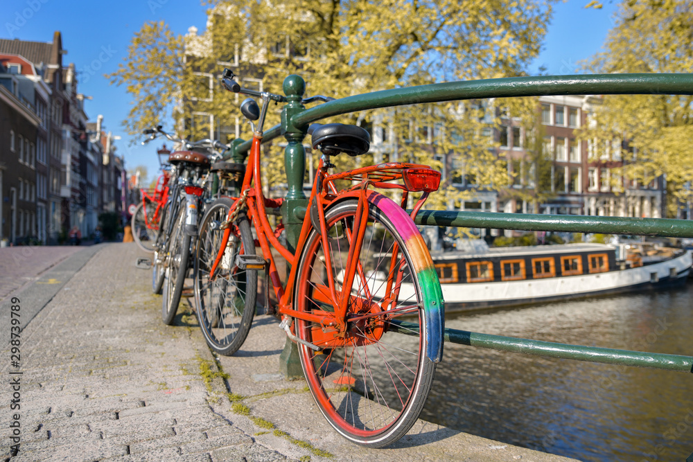 Orange bike with LGBT flag parked on a bridge in Amsterdam, Netherlands