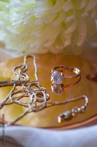 The golden chain and ring with diamond near flower, close up.