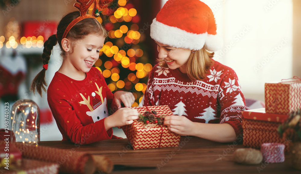 happy family mother and child pack Christmas gifts at home near Christmas tree. happy family mother and child pack Christmas gifts at home near Christmas tree.