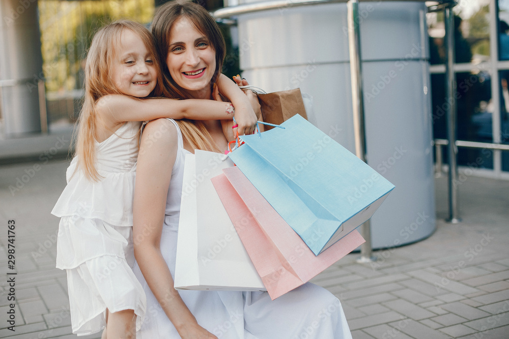 Beautiful girl in a summer city. Lady with shopping bags. Mother with daughter in stylish clothes Beautiful girl in a summer city. Lady with shopping bags. Mother with daughter in stylish clothes