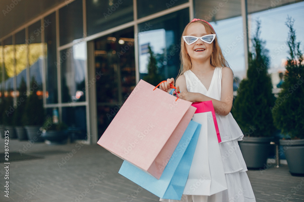 Beautiful girl in a summer city. Child with shopping bags Beautiful girl in a summer city. Child with shopping bags