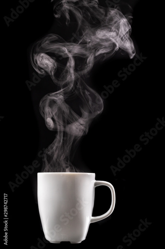 A white mug of warm drink and steam. Tasty hot coffee on a dark table.