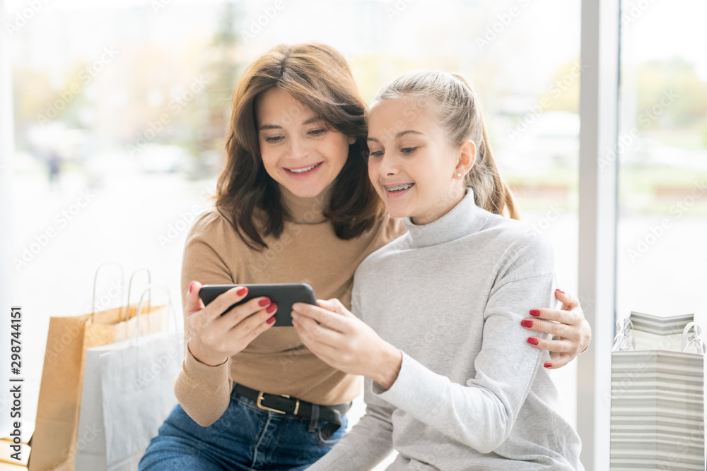 Joyful young mother and her daughter using video-chat in smartphone Joyful young mother and her daughter using video-chat in smartphone