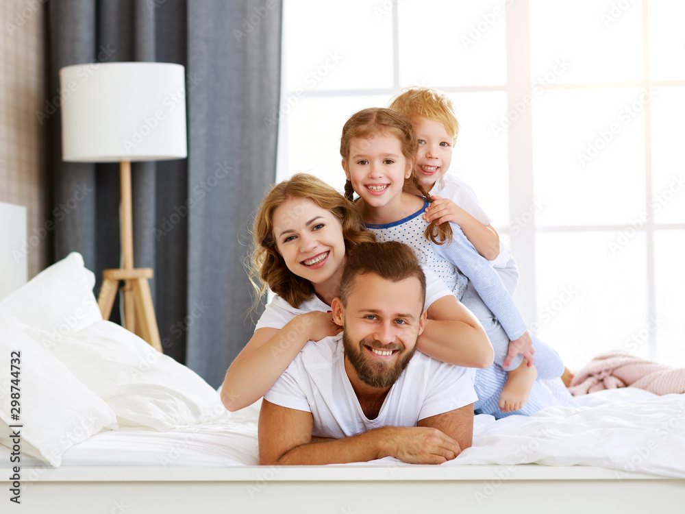 happy family mother, father and children laughing, playing and smiling in bed at home. happy family mother, father and children laughing, playing and smiling in bed at home.