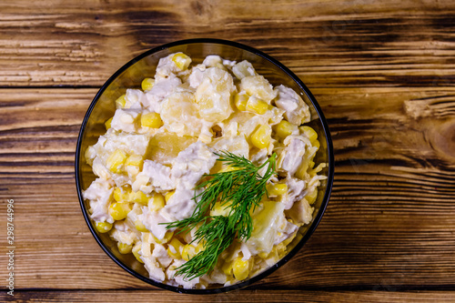 Festive salad with chicken breast, canned pineapple, cheese, sweet corn and mayonnaise on wooden table. Top view