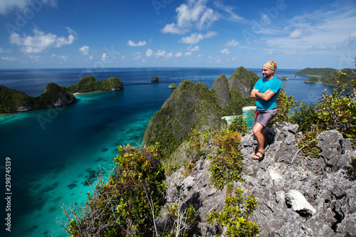 Tourists are on the top of the cliff of remote archipelago Pulau Wayag, Raja Ampat, Indonesia