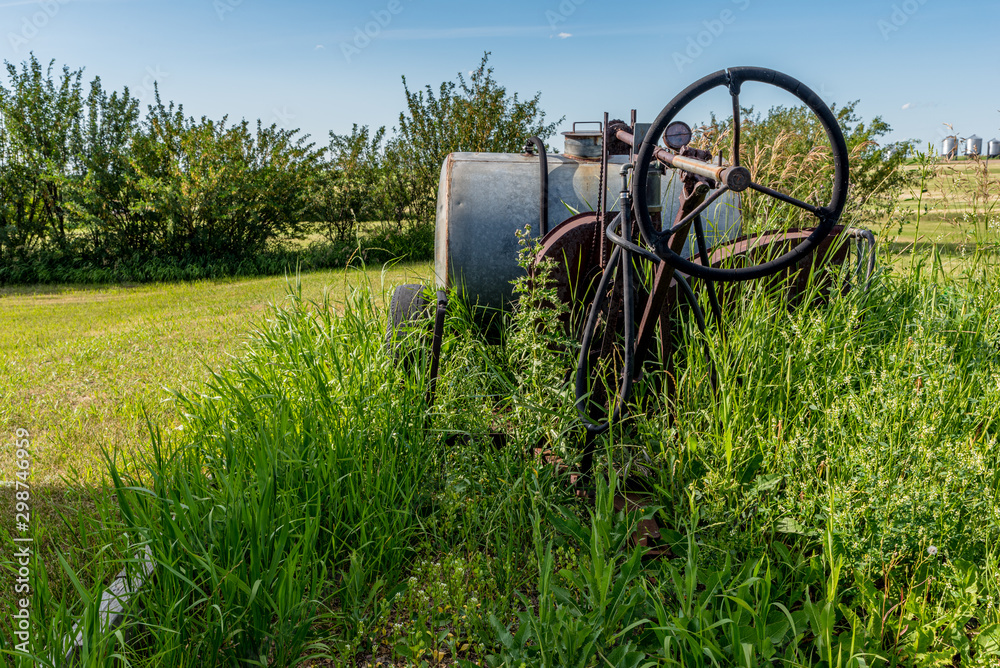 Vintage farming pull-type sprayer surrounded by tall grass