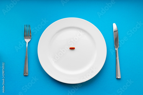 A small tablet in a plate. Medical concept. Eat pills instead of food.