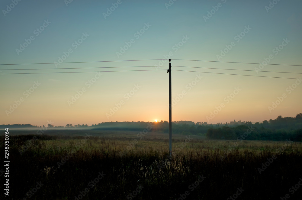 Collective farm at dawn. Grain sown field, fog, horizon, electric wires and pole, Vladimir Region, Russia