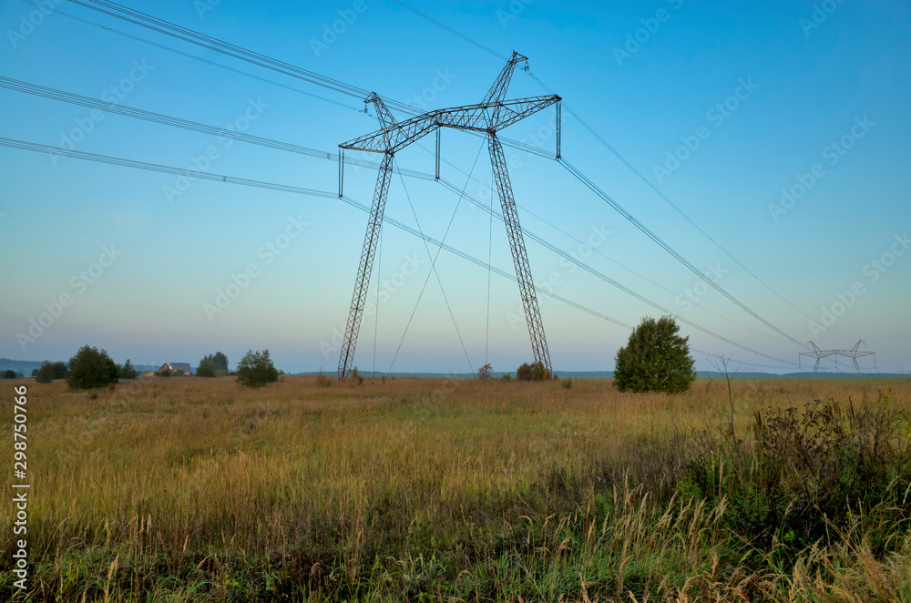 In the village at dawn. Grain sown field, fog, horizon, electric wires and metal power poles, Russia