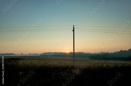 Collective farm at dawn. Grain sown field, fog, horizon, electric wires and pole, Vladimir Region, Russia