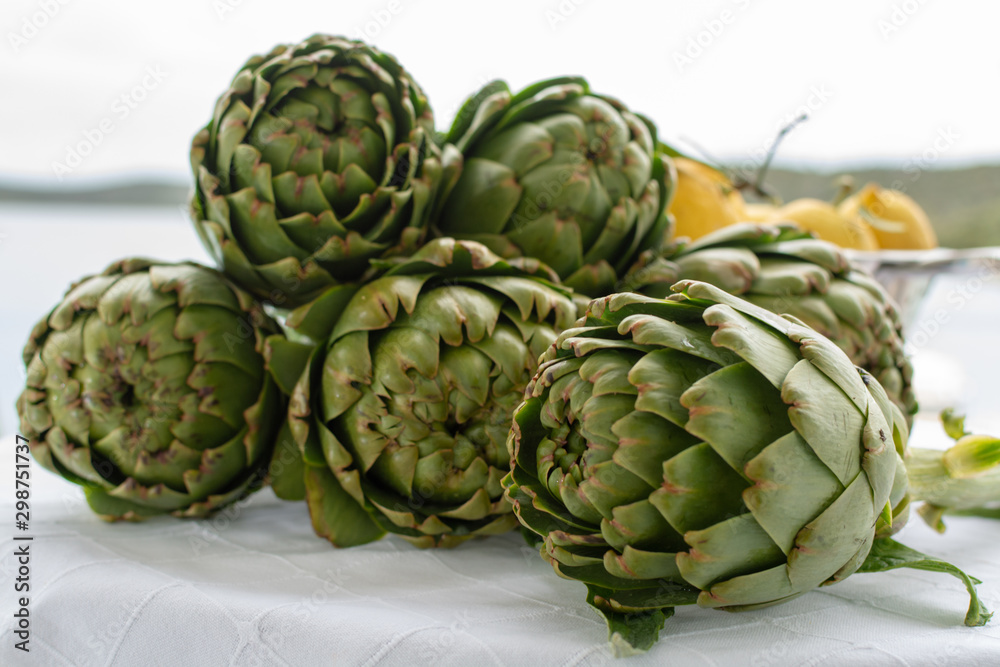 Obraz premium Bunch of fresh raw artichokes heads from artichoke plantation in Argolida, Greece ready to cook with lemon