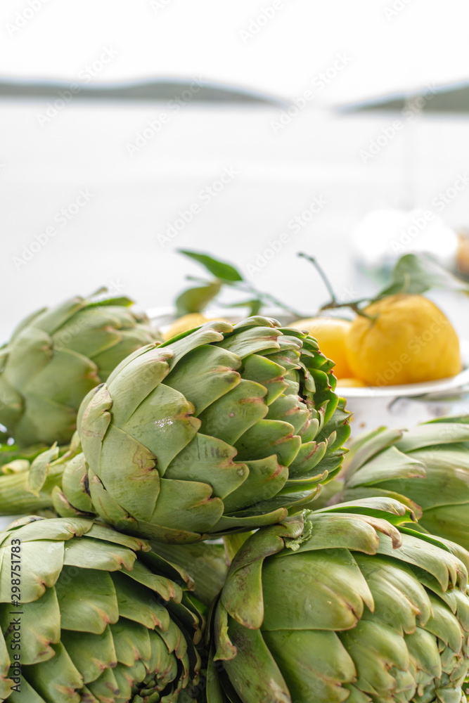 Fototapeta premium Bunch of fresh raw artichokes heads from artichoke plantation in Argolida, Greece ready to cook with lemon