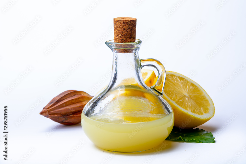 Fresh lemon juice made from ripe yellow Sicilian lemons used for cooking in glass bottle on olive wood plate Fresh lemon juice made from ripe yellow Sicilian lemons used for cooking in glass bottle on olive wood plate
