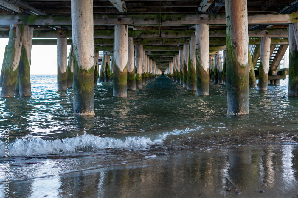View on sea or ocean water onder old wooden pier or bridge