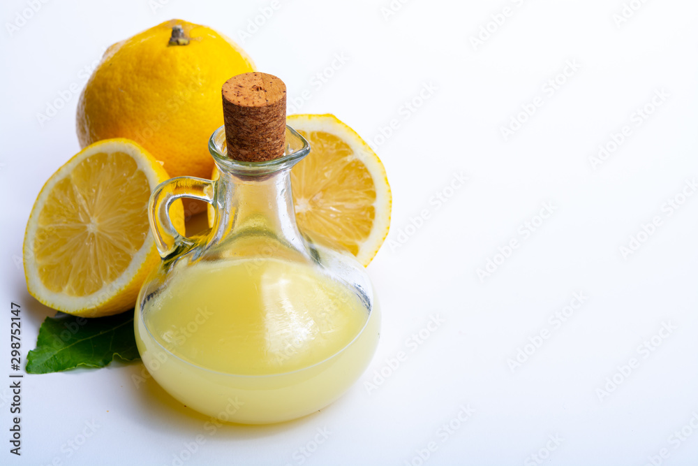 Fresh lemon juice made from ripe yellow Sicilian lemons used for cooking in glass bottle on olive wood plate Fresh lemon juice made from ripe yellow Sicilian lemons used for cooking in glass bottle on olive wood plate