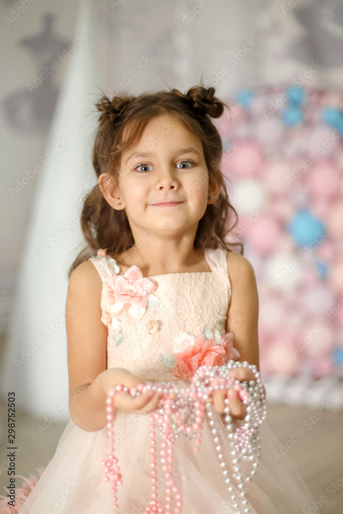 Little girl in a white dress plays with beads Little girl in a white dress plays with beads