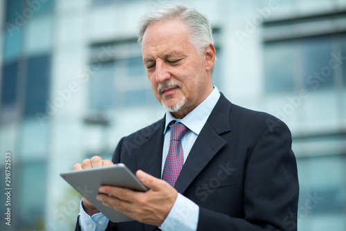 Executive using his tablet in front of his office