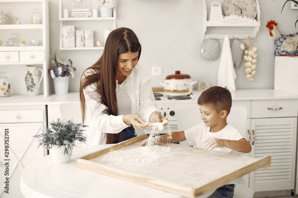 Family in a kitchen. Beautiful mother with little son. Flour at the table Family in a kitchen. Beautiful mother with little son. Flour at the table