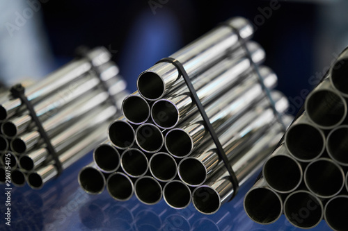 Steel pipes against industrial blurred background, close-up