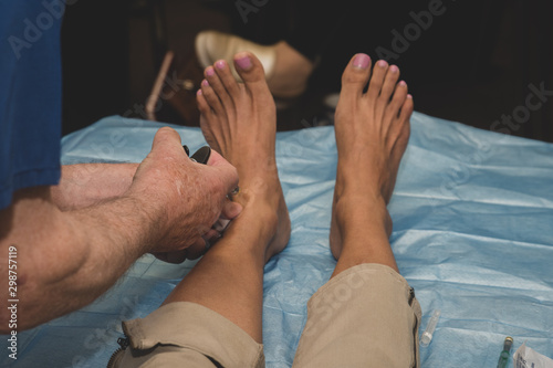 Podiatrist or foot surgeon performs an ankle injection of local anaesthetic to numb the food for awake surgery or procedure. 