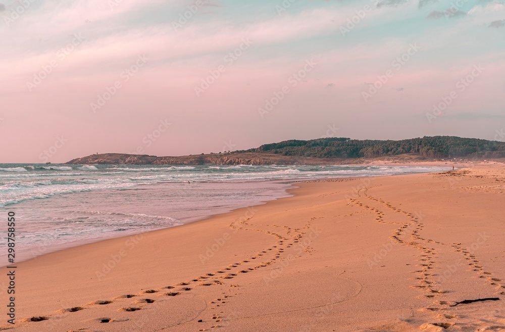 Playa idílica y solitaria en otoño con línea de huellas sobre la arena