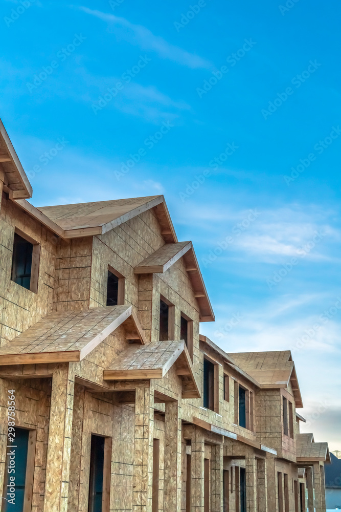 Construction of townhouses viewed against blue sky and clouds on a sunny day