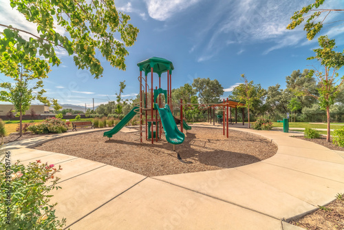 Green slides at a neighborhood playground surrounded by trees on a sunny day photo