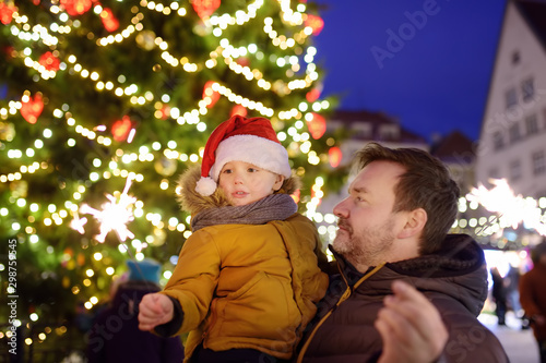 Little boy and his father with sparklers near giant Christmas fir tree on fair in Tallinn, Estonia.