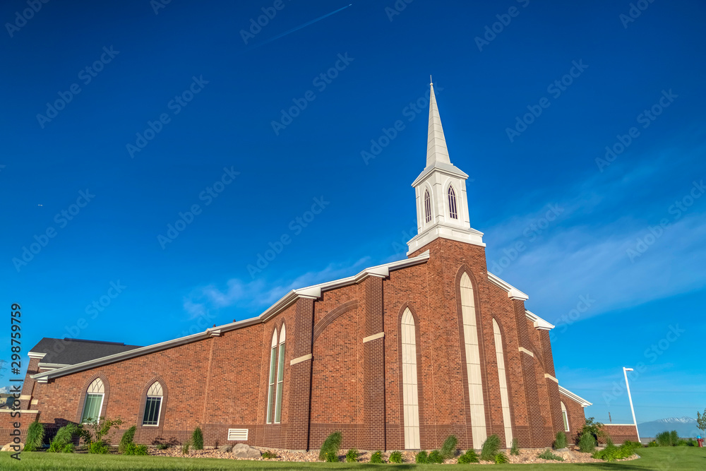 Sunny day view of a church with white steeple and vibrant blue sky background