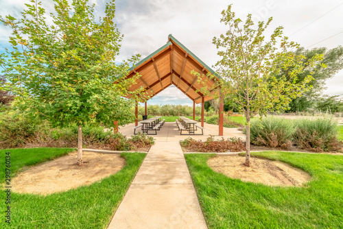 Beautiful view of a picnic pavilion at a park with pathway and trees in front