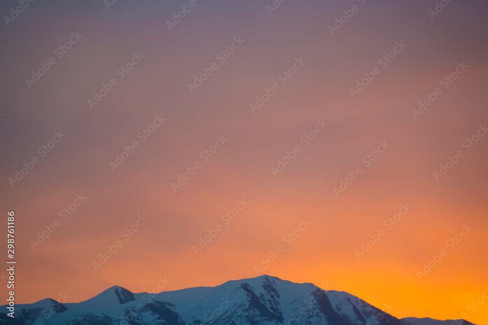 Beautiful view of a mountain peak covered with snow during winter at sunset