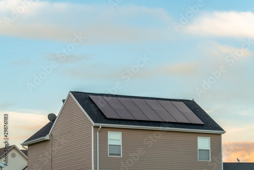 Exterior view of a home with solar panels on the roof under blue sky and clouds