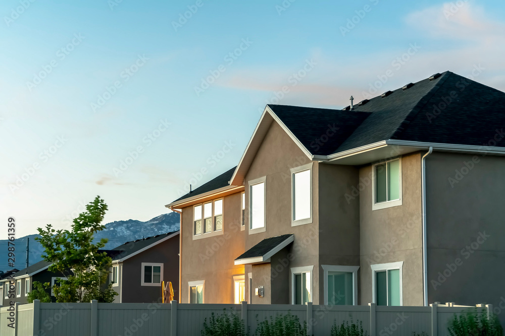 Family home surrounded by a white fence with mountain and sky in the background Family home surrounded by a white fence with mountain and sky in the background
