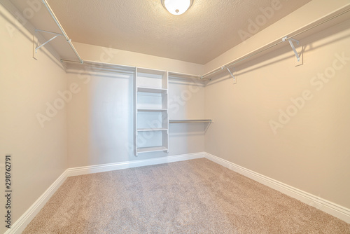 Empty white walk in closet with bare shelving