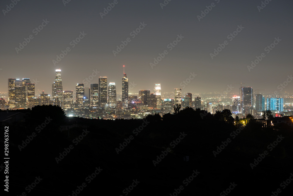 Night skyline view of downtown Los Angeles with hilltop ridgeline near Griffith Park in Southern California.  